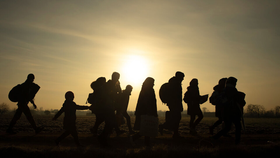 Silhouette of migrants walking at sunset