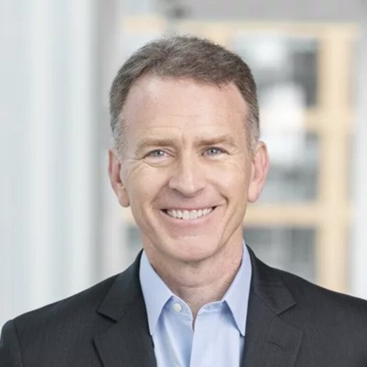 Smiling man in business attire with blurred office background.